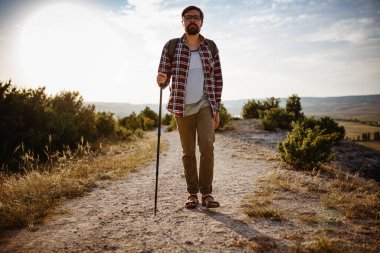 Adam dağlarda sırıkla yürüyüp başka tarafa bakıyor. Turizm kavramı ve açık havada dağlarda kolay bir yürüyüş.