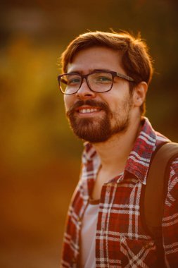 Sırt çantalı genç gezgin arka planda kayalık dağlarla dışarıda dinleniyor. Yaşam tarzı ve hobi konsepti