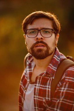 Sırt çantalı genç gezgin arka planda kayalık dağlarla dışarıda dinleniyor. Yaşam tarzı ve hobi konsepti