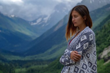 Dağların tepesinde yürüyen şık bir bayan hippi. Güneşli dağları keşfeden mutlu genç bir kadın. Seyahat ve seyahat tutkusu konsepti. İnanılmaz atmosferik bir an. Kuzey Kafkasya, Dombai, Rusya.
