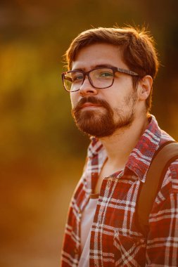 Sırt çantalı genç gezgin arka planda kayalık dağlarla dışarıda dinleniyor. Yaşam tarzı ve hobi konsepti