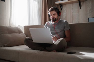 Evde kulaklıklı ve defterli bir adam var. Genç hipster internetten kulaklık takıyor. Dizüstü bilgisayarda Webinar Podcast izliyor. Eğitim kursu ya da müzik dinliyor.