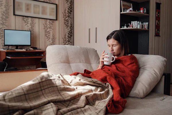 Sick and Flu Woman. Caught Cold. Woman feeling cold with blanket resting on the sofa at home