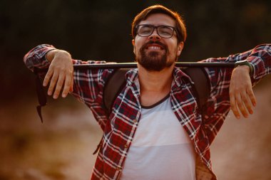 Sırt çantalı genç gezgin arka planda kayalık dağlarla dışarıda dinleniyor. Yaşam tarzı ve hobi konsepti