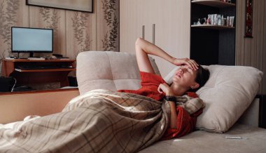 Hasta ve Grip Kadın. Soğuk algınlığına yakalandım. Kadın kendini üşümüş hissediyor. Evdeki kanepede dinleniyor.