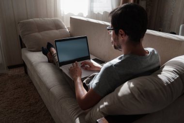 Uzaktan kumanda. Dizüstü bilgisayarda çalışan bir adam evdeki koltukta oturuyor. Metin için Boşluğu Kopyala. Serbest çalışan hipster, ortaklarıyla çalışır, çalışır ya da iletişim kurar.