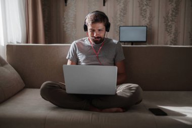 Evde kulaklıklı ve defterli bir adam var. Genç hipster internetten kulaklık takıyor. Dizüstü bilgisayarda Webinar Podcast izliyor. Eğitim kursu ya da müzik dinliyor.