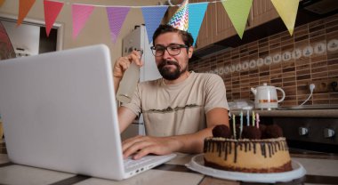 Karantina zamanında doğum gününü kutlayan bir adam. Arkadaşlarıyla sanal parti aracılığıyla doğum gününü kutlayan adam. Coronavirüs salgını 2020.