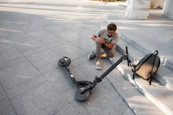 Young Man Accident With An Electric Scooter On Street. A man fell from a scooter on a city street.