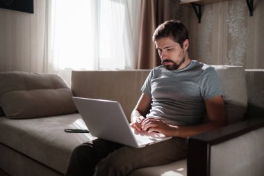 Uzaktan kumanda. Dizüstü bilgisayarda çalışan bir adam evdeki koltukta oturuyor. Metin için Boşluğu Kopyala. Serbest çalışan hipster, ortaklarıyla çalışır, çalışır ya da iletişim kurar.