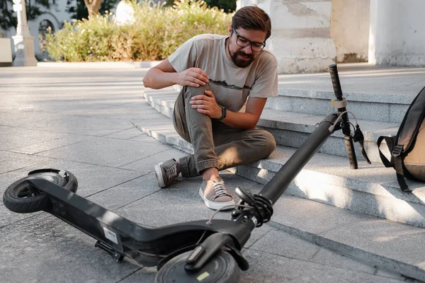 Young Man Accident With An Electric Scooter On Street. A man fell from a scooter on a city street.