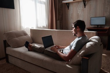 Uzaktan kumanda. Dizüstü bilgisayarda çalışan bir adam evdeki koltukta oturuyor. Metin için Boşluğu Kopyala. Serbest çalışan hipster, ortaklarıyla çalışır, çalışır ya da iletişim kurar.