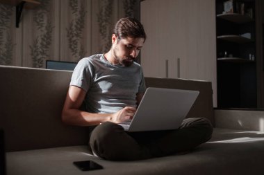 Uzaktan kumanda. Dizüstü bilgisayarda çalışan bir adam evdeki koltukta oturuyor. Metin için Boşluğu Kopyala. Serbest çalışan hipster, ortaklarıyla çalışır, çalışır ya da iletişim kurar.