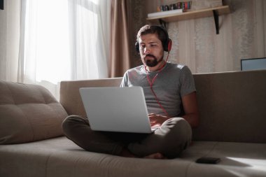 Evde kulaklıklı ve defterli bir adam var. Genç hipster internetten kulaklık takıyor. Dizüstü bilgisayarda Webinar Podcast izliyor. Eğitim kursu ya da müzik dinliyor.