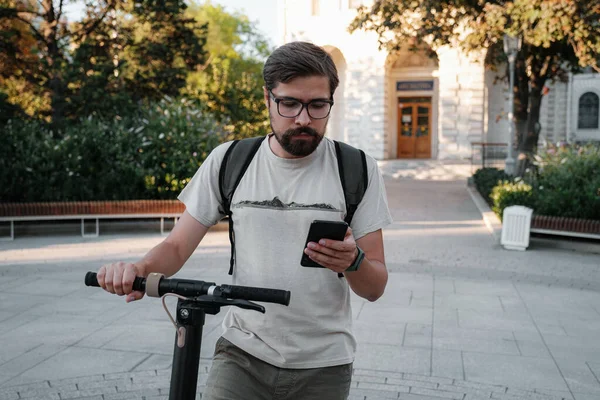 Hipster Człowiek Dojeżdżający Elektrycznym Skuterem Świeżym Powietrzu Mieście Pomocą Smartfona — Zdjęcie stockowe