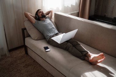 Evde kulaklıklı ve defterli bir adam var. Genç hipster internetten kulaklık takıyor. Dizüstü bilgisayarda Webinar Podcast izliyor. Eğitim kursu ya da müzik dinliyor.