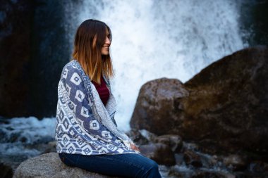 Şelalenin yanında oturan güzel kadın yürüyüşçü. Mutlu bir kadınla ekolojik konsept imajı. Şelale Shumka, Dombai, Karachay-Çerkessia, Rusya