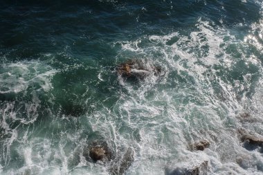 Okyanus dalgası arka planı deniz suyunu kırıyor kayalık kıyı dalgalı deniz turkuaz su gradyan köpüğü. Açık denizde büyük dalgalar. Yaz musonu. Bir deniz dalgasının beyaz tepesi.