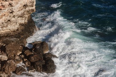 Okyanus dalgası arka planı deniz suyunu kırıyor kayalık kıyı dalgalı deniz turkuaz su gradyan köpüğü. Açık denizde büyük dalgalar. Yaz musonu. Bir deniz dalgasının beyaz tepesi.