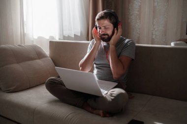 Evde kulaklıklı ve defterli bir adam var. Genç hipster internetten kulaklık takıyor. Dizüstü bilgisayarda Webinar Podcast izliyor. Eğitim kursu ya da müzik dinliyor.