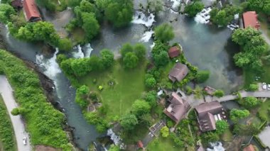 Slunj ve Korana nehirlerindeki Rastoke su değirmeni köyü. Şelaleleri, ahşap evleri, nehirleri akan sevimli Rastoke köyü. Hırvatistan 'ın göbeğindeki peri masalı bahar mevkiinin havadan görünüşü