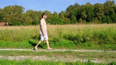Tarlalar ve ormanlarla çevrili kırsal toprak yolda yürüyen bir adam kırsal hayatın huzurlu ve kırsal atmosferini yakalıyor. Yalnızlığı ve doğayı vurgulayan basit, sessiz bir sahne..