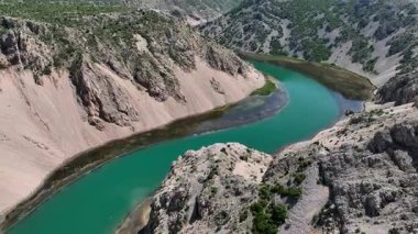 Obrovac 'tan nehir ağzı antenine kadar Zrmanja kanyonu nehri. Dolambaçlı Zrmanja nehrinin havadan çekimleri derin kanyonu, bereketli bahar renklerini ve uzak yolları kesiyor.