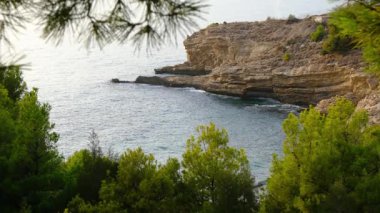 Cala Tio Ximo kıyı şeridi Aralık akşamında ele geçirildi. Sakin kış denizi, yumuşak gün batımı parıltısı, Benidorm yakınlarındaki küçük adanın huzurlu manzarası. Sessiz doğal güzellik, insan yok, sadece deniz ve gökyüzü..