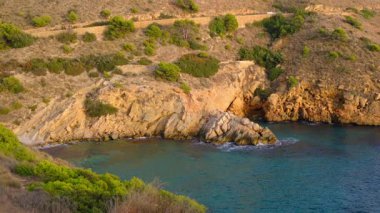 Cala Tio Ximo kıyı şeridi Aralık akşamında ele geçirildi. Sakin kış denizi, yumuşak gün batımı parıltısı, Benidorm yakınlarındaki küçük adanın huzurlu manzarası. Sessiz doğal güzellik, insan yok, sadece deniz ve gökyüzü..