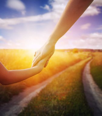 Anne ve kızı birbirlerine yol ve güneş alanını tutan eller