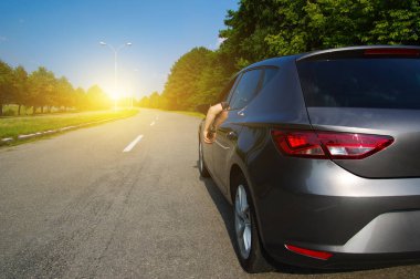  Doğada asfalt yolda bir araba. Erkek eli dinleniyor ve yol gezisinin ve güneşli günün tadını çıkarıyor..