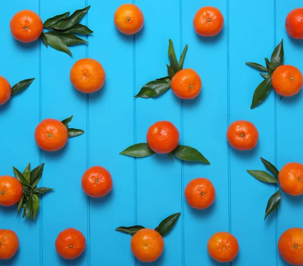 tangerines with green leaves on turquoise wooden background. Top view.