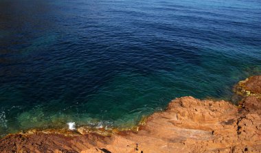 Denizin taşlı manzarası. Koyda berrak mavi su.