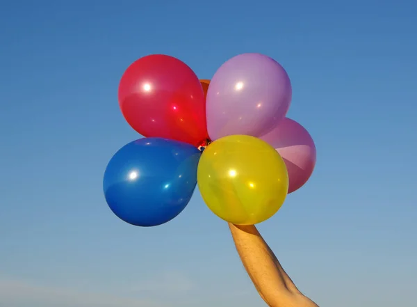 hand holding colorful balloons on sky