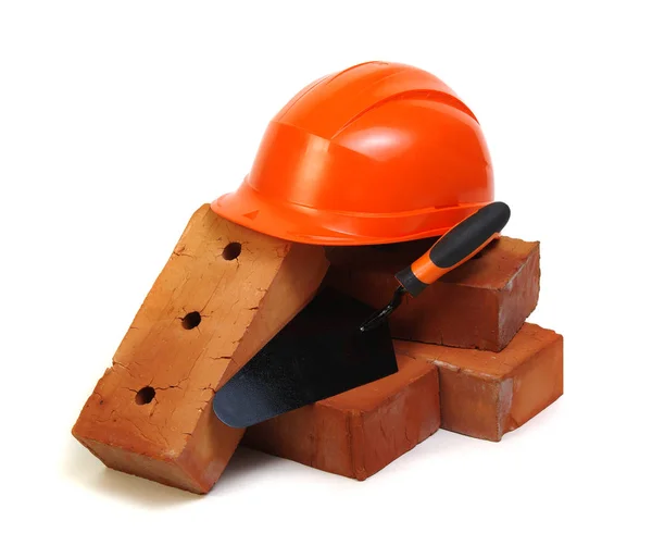 Brick, red hard hat and tools isolated on white background