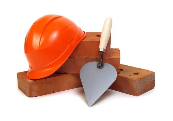 Brick, red hard hat and tools isolated on white background