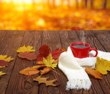 Sonbahar yaprakları ve sıcak bir fincan kahve. Güneş ışığı arka planında tahta masa. Sonbahar zaman kavramı.