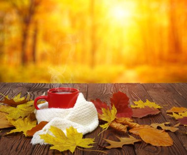 Sonbahar yaprakları ve sıcak bir fincan kahve. Güneş ışığı arka planında tahta masa. Sonbahar zaman kavramı.