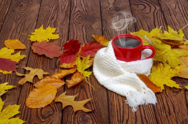  Bir fincan sıcak kahve ve ahşap masa zemininde bir eşarp. Sonbahar yaprakları. Mevsimlik, durgun yaşam konsepti.