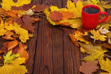 Sonbahar yaprakları, ahşap arka planda sıcak bir kahve fincanı.. 