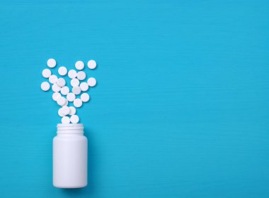 Çeşitli ilaç hapları, haplar, kapsüller ve mavi arka planda beyaz şişe. Uzayı metin için kopyala. Düz yatıyordu. Üst görünüm