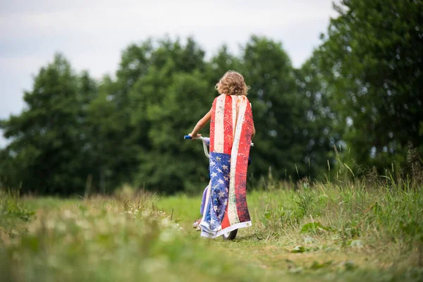 Symbol of celebration 4 fourth of july. Young Girl riding bicycle with american flag in hand — Stock Photo, Image