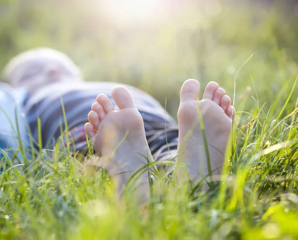快乐的小男孩躺在绿草户外在春天公园 — 图库照片