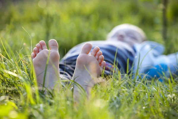 快乐的小男孩躺在绿草户外在春天公园 — 图库照片
