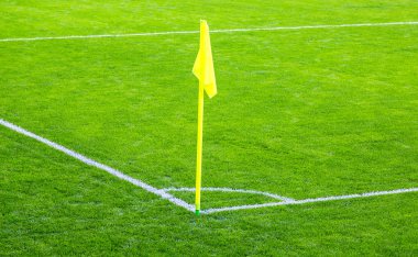 Yeşil futbol sahası üzerinde sarı köşe bayrak
