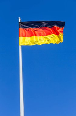 Rüzgara karşı mavi gökyüzü uçan Almanya bayrağı