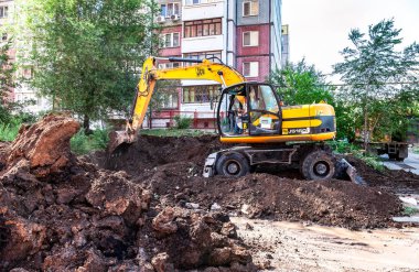 Samara, Rusya - 25 Mayıs 2017: yaz güneşli bir günde apartment building yakınındaki bir siper kazma sarı Ekskavatör