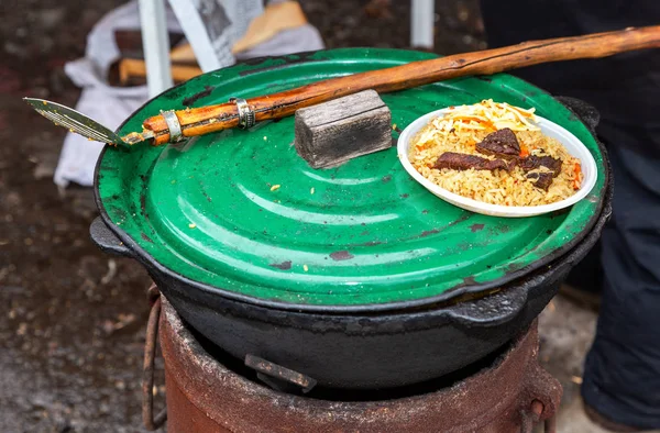 Kochen traditioneller usbekischer Pilaf in einem großen Kessel — Stockfoto