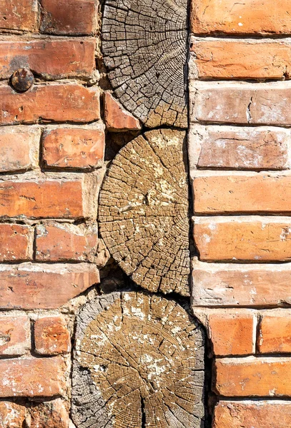 Vintage red brick wall with wooden logs — Stock Photo, Image