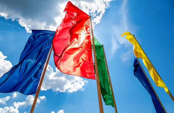 Kolorowe flagi na wietrze przed błękitnym niebem — Zdjęcie stockowe
